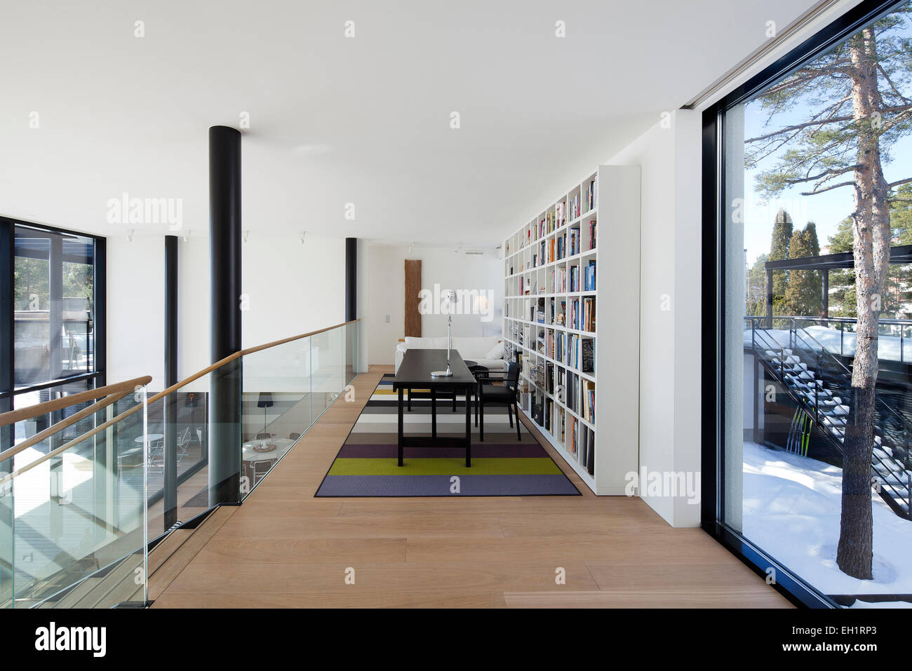 Mezzanine avec table, bibliothèque et photo fenêtre dans la salle blanche en maison privée dans le Westend, Espoo, Finlande Banque D'Images