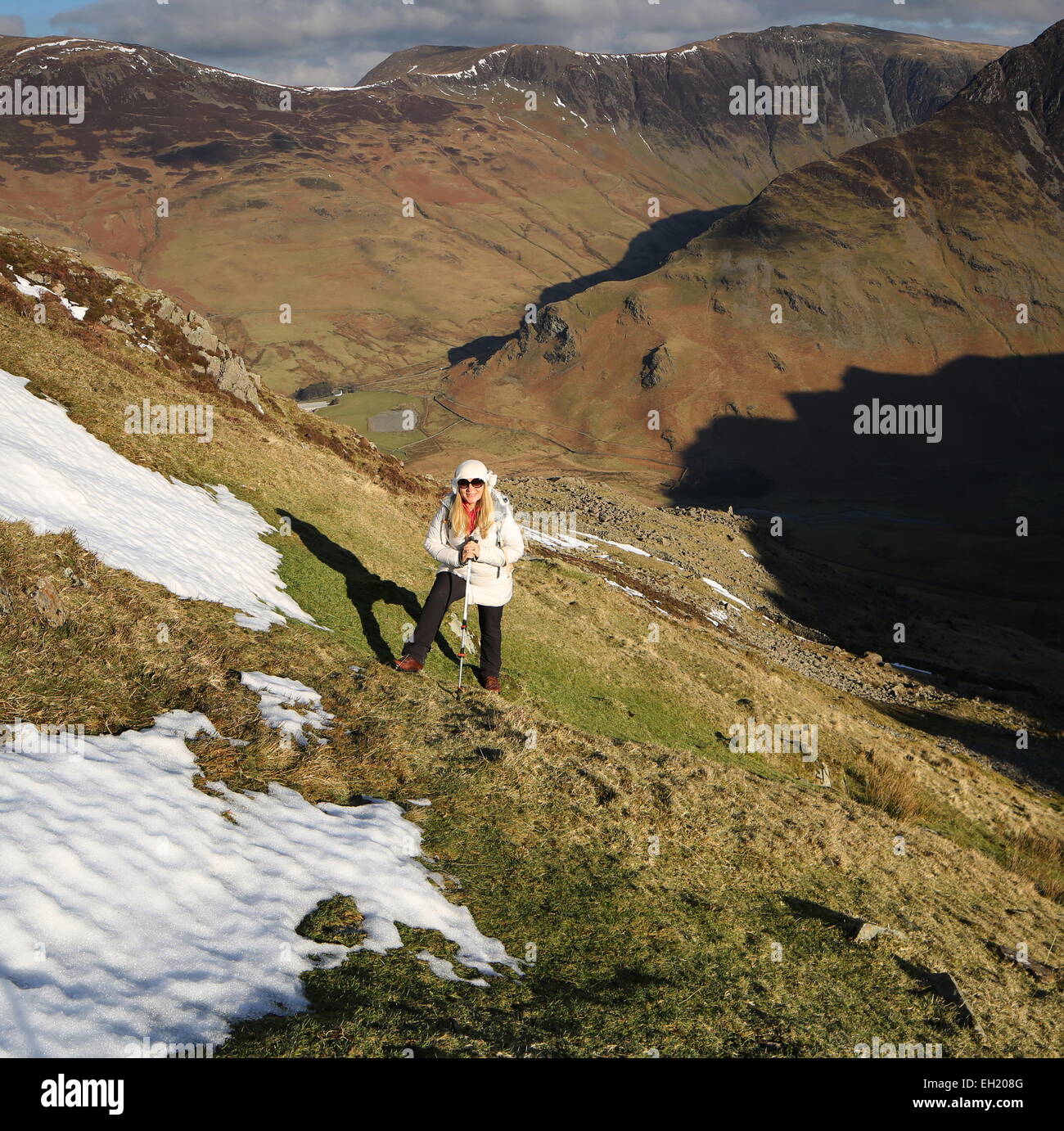 Female hiker escalade de rocher haute lande. Fleetwith Pike et Honister Pass au-delà Banque D'Images
