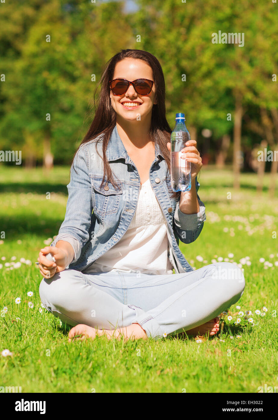 Souriante jeune fille avec une bouteille d'eau dans la région de park Banque D'Images