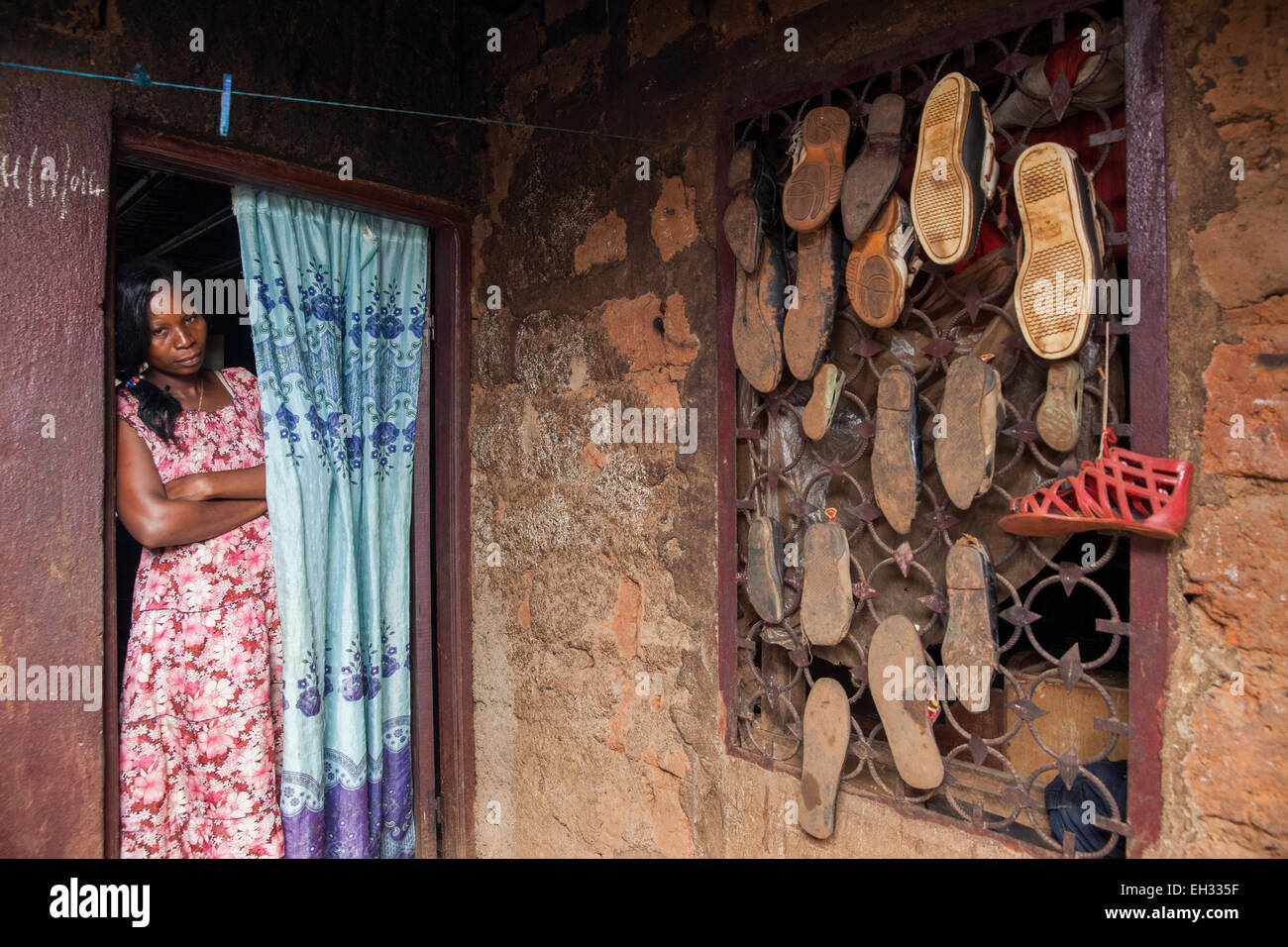 Bamenda, Cameroun, juillet 2013 : une femme résident. Accrocher les chaussures sur la fenêtre barres pour sécher dans la saison des pluies. Banque D'Images