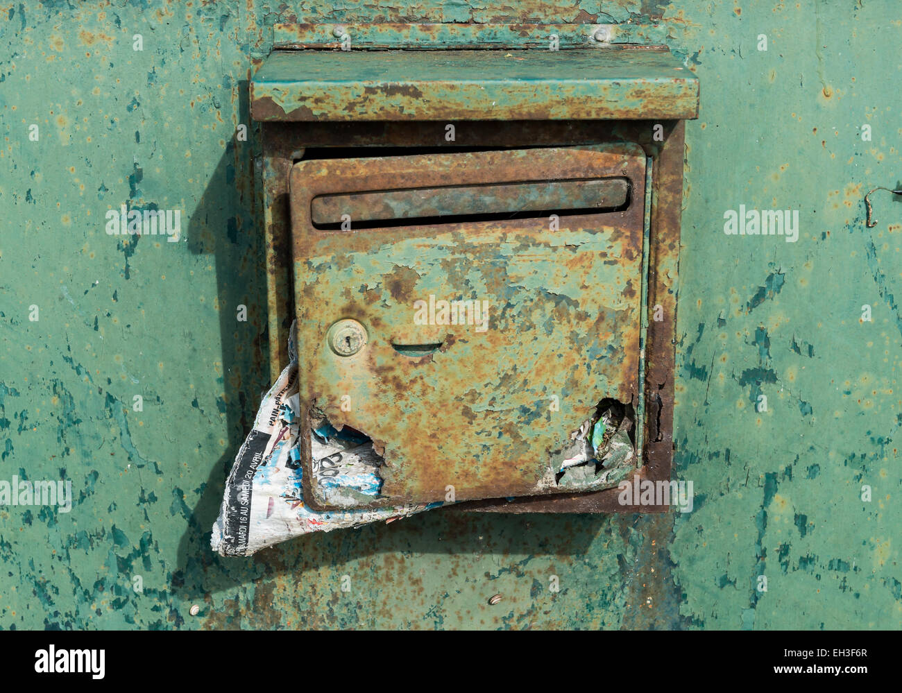 Ancienne boîte aux lettres verte avec de la rouille et un trou et sale courrier sur une porte métallique verte. Banque D'Images