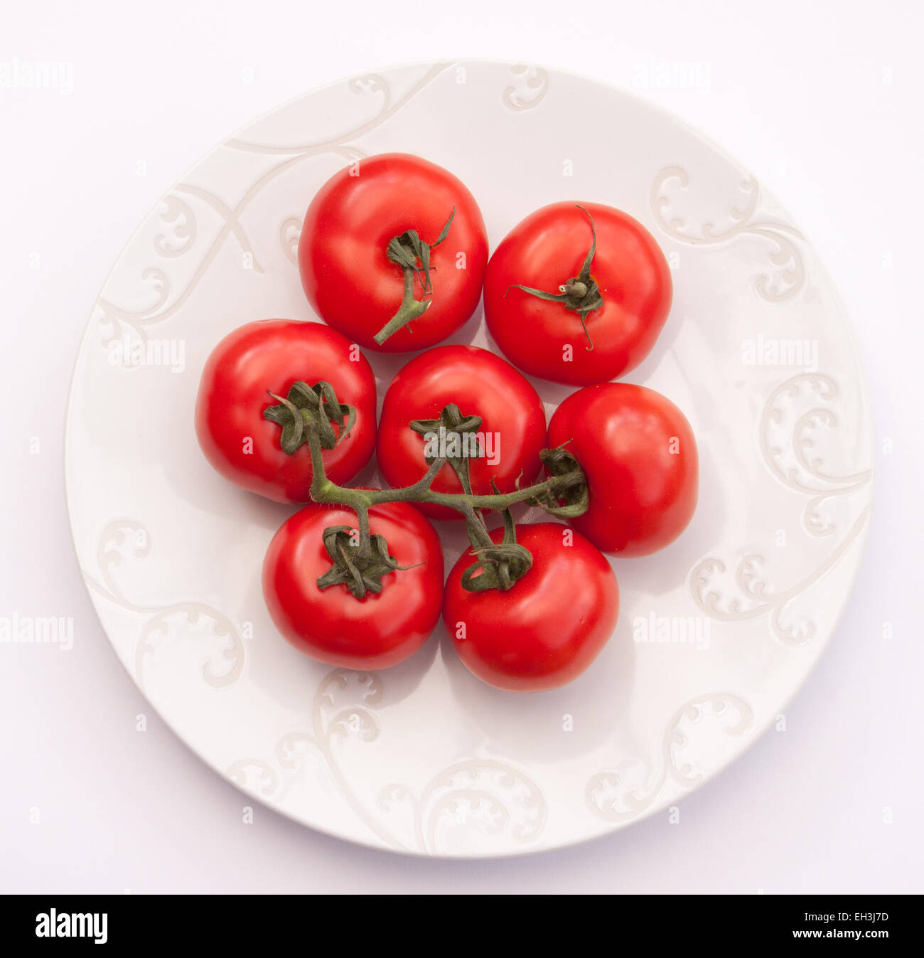 Grandes tomates Beefsteak sur la vigne sur une plaque blanche. Banque D'Images