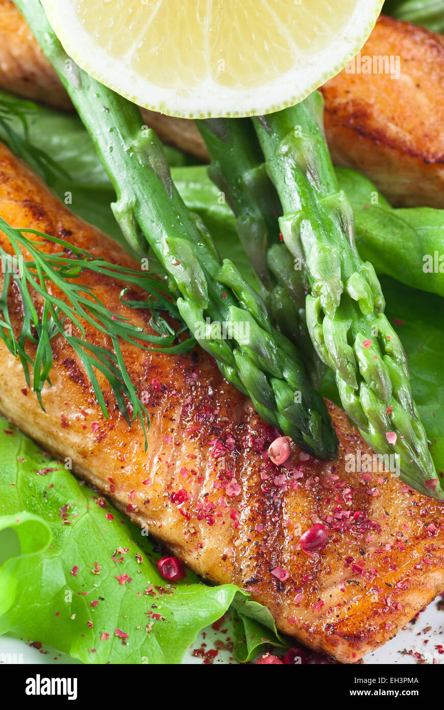 Saumon poêlé aux asperges vertes. Garnie d'aneth et citron. Banque D'Images