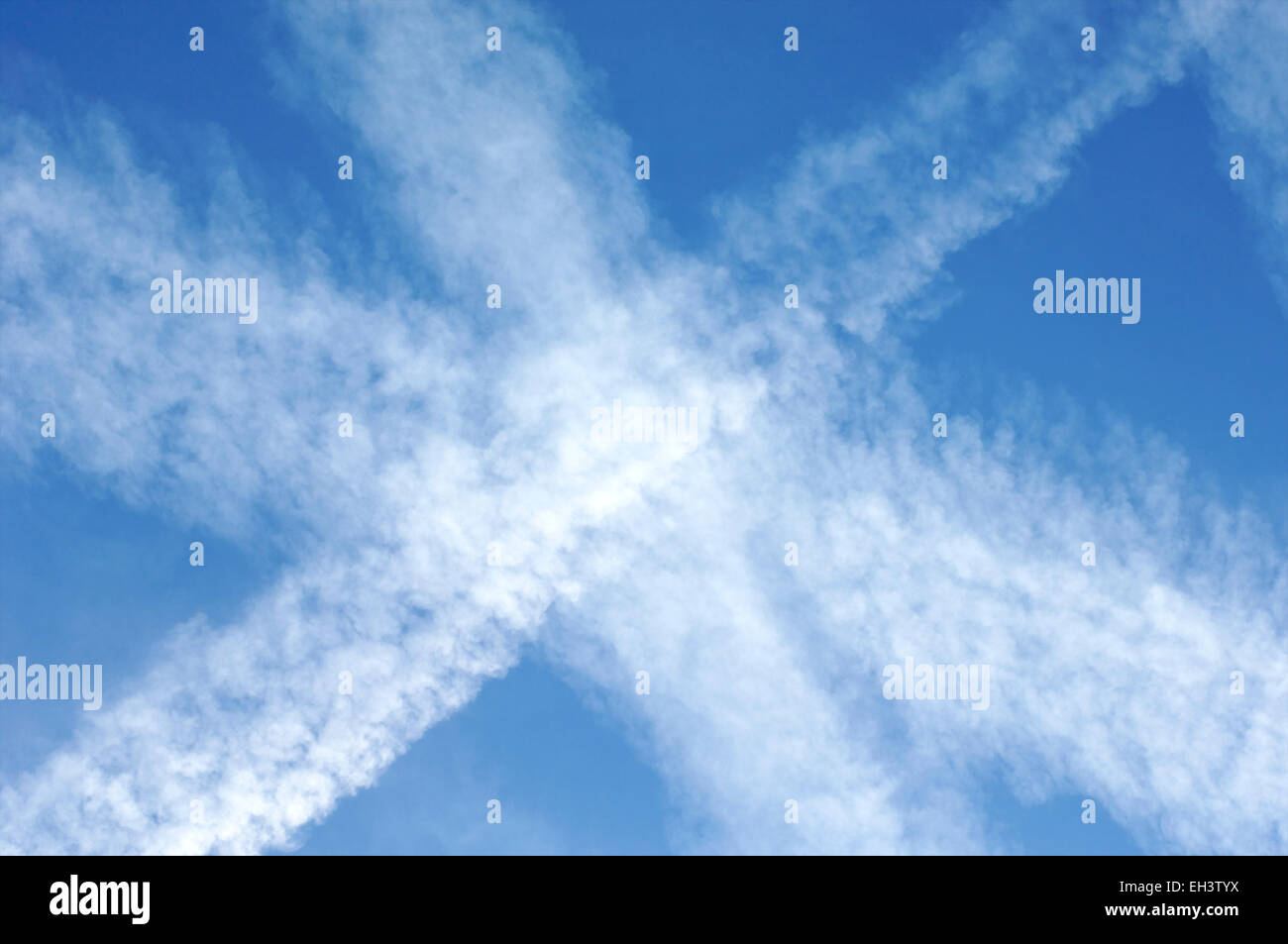 Ciel bleu avec des chemtrails laissées par les avions dans l'air couvrant un ciel bleu avec des nuages artificiels contenant des métaux toxiques et des produits chimiques Banque D'Images
