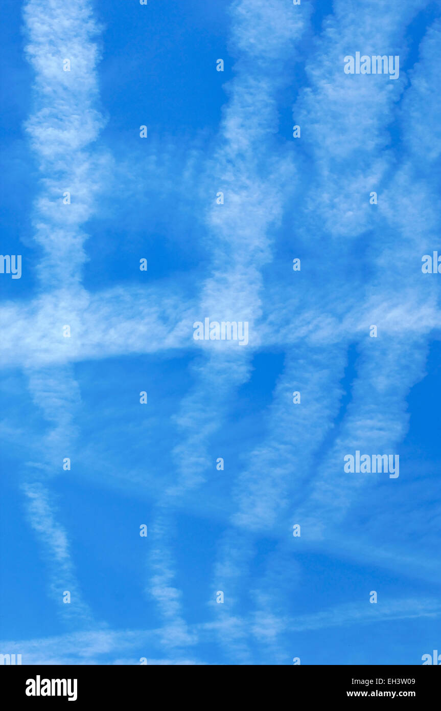 Ciel bleu avec des chemtrails laissées par les avions dans l'air couvrant un ciel bleu avec des nuages artificiels contenant des métaux toxiques et des produits chimiques Banque D'Images