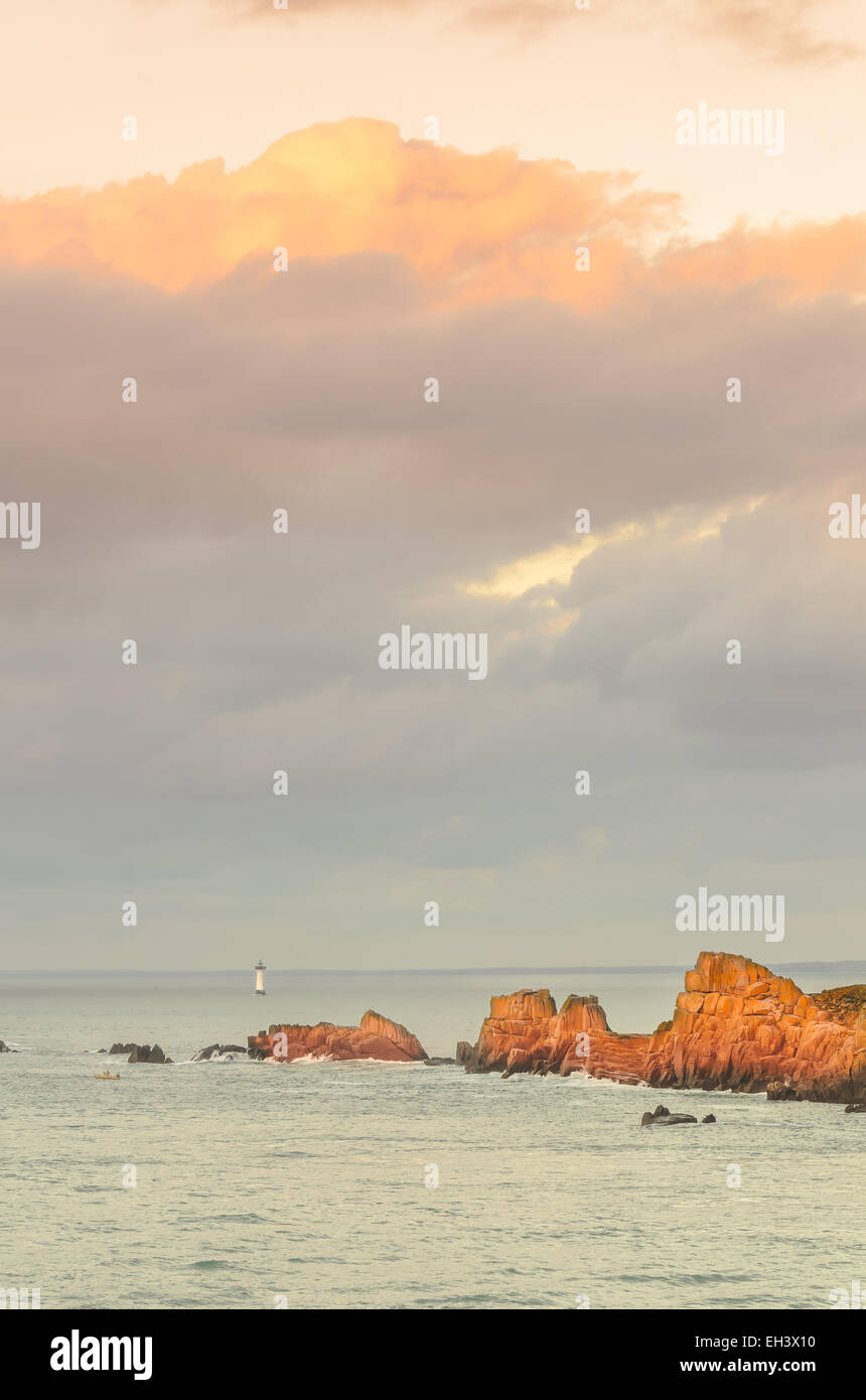 Sous les grandes falaises ciel nuageux avec phare, situé à distance, des rochers éclairés par les rayons du soleil dernière avant le coucher du soleil, du soleil, de Saint Malo, Banque D'Images