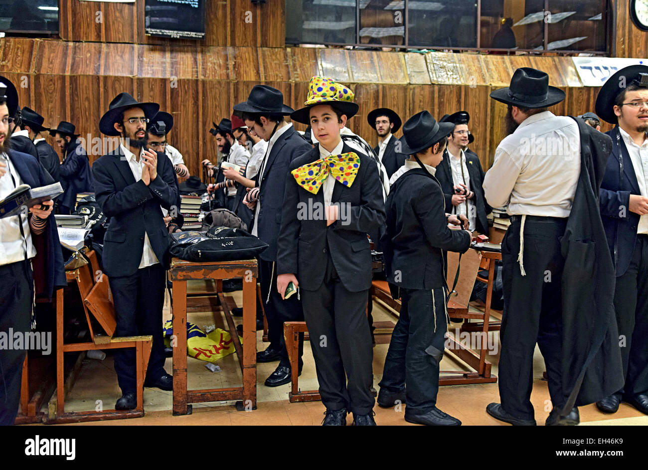 Un groupe de religieux juifs, hommes y compris, dont un dans un costume de Pourim dans une synagogue à Brooklyn, New York. Banque D'Images