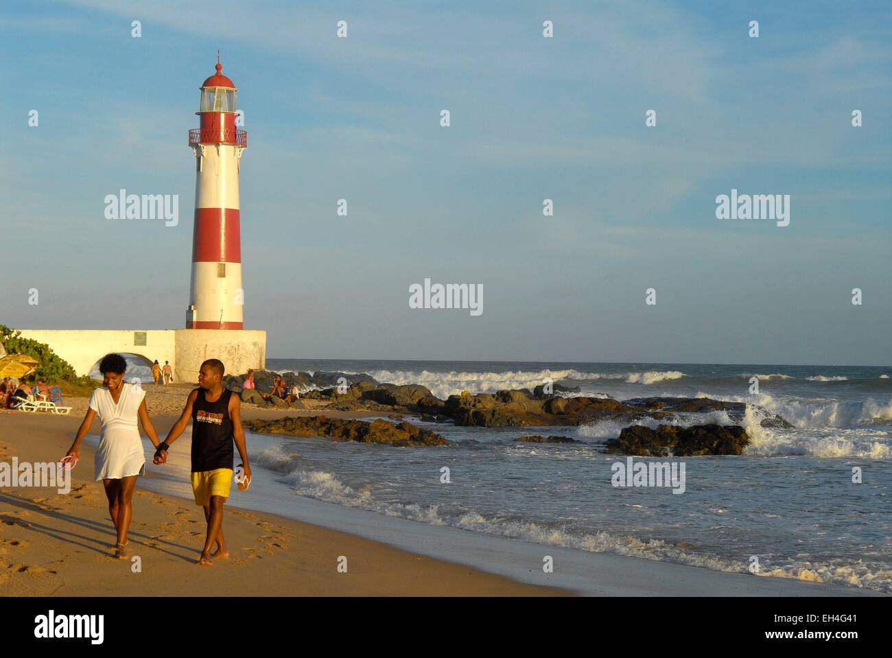 Le Brésil, l'Etat de Bahia, Itapua, Itapua beach et phare au coucher du soleil, couple holding hands walking on the beach Banque D'Images