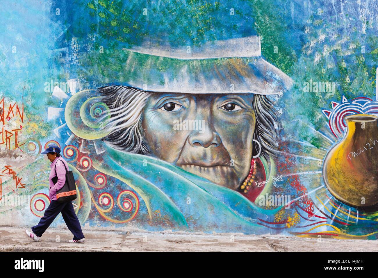L'Équateur, Imbabura, Atuntaqui, occupé équatorien femme moderne en face d'un mur d'écriture graffiti représentant une femme traditionnelle des Andes Banque D'Images