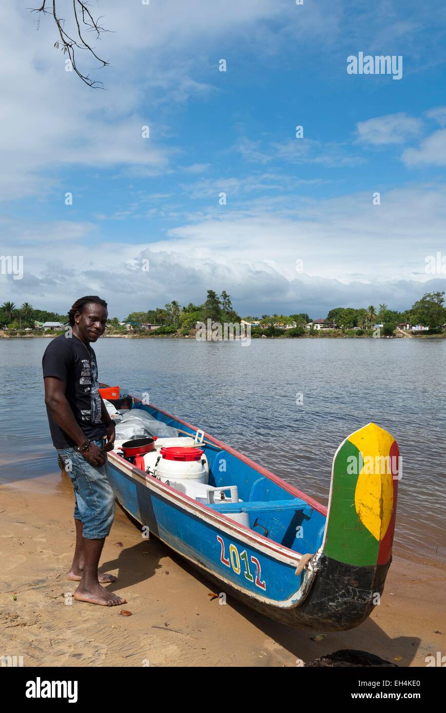 République du Suriname, Lawa River En aval du fleuve Maroni en pirogue, en charge et échouée sur le côté rive Suriname, portrait d'un passeur (Seke), dans l'arrière-plan le village de Grand-Santi Banque D'Images