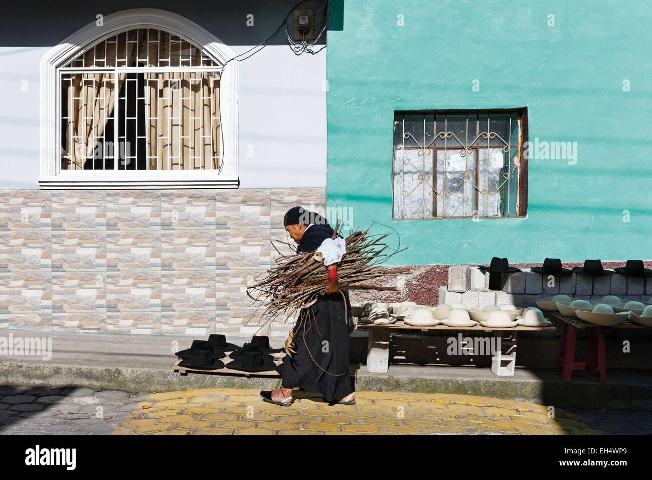 L'Équateur, Imbabura, Iluman, vieille femme vêtue traditionnellement portant un paquet de bois sur une rue ou un chapeau de feutre de l'artisanat à sec Banque D'Images