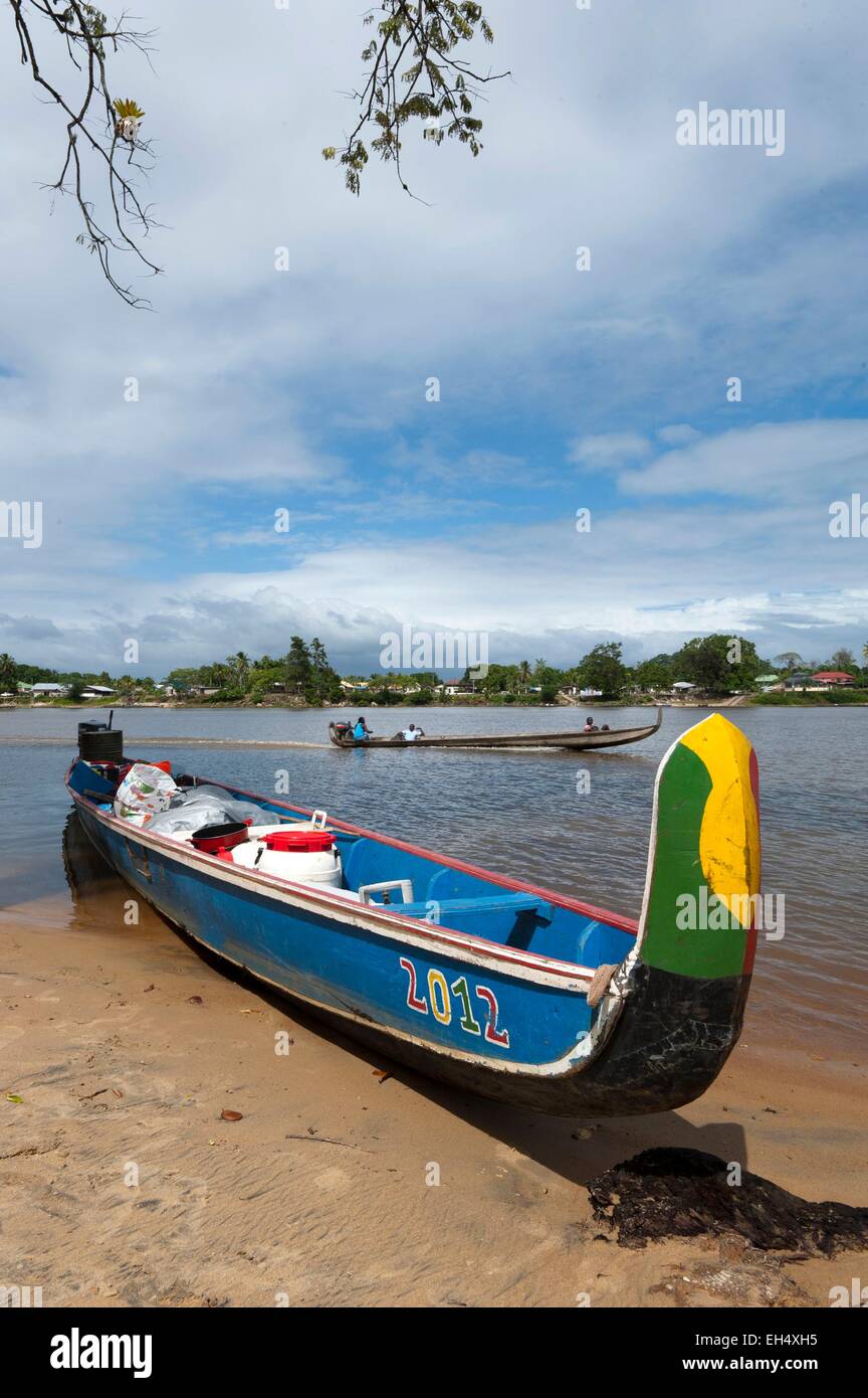 République du Suriname, Lawa River En aval du fleuve Maroni en pirogue, en charge et échoués sur la rive côté surinamais et pirogue naviguant sur le fleuve, dans l'arrière-plan le village de Grand-Santi Banque D'Images