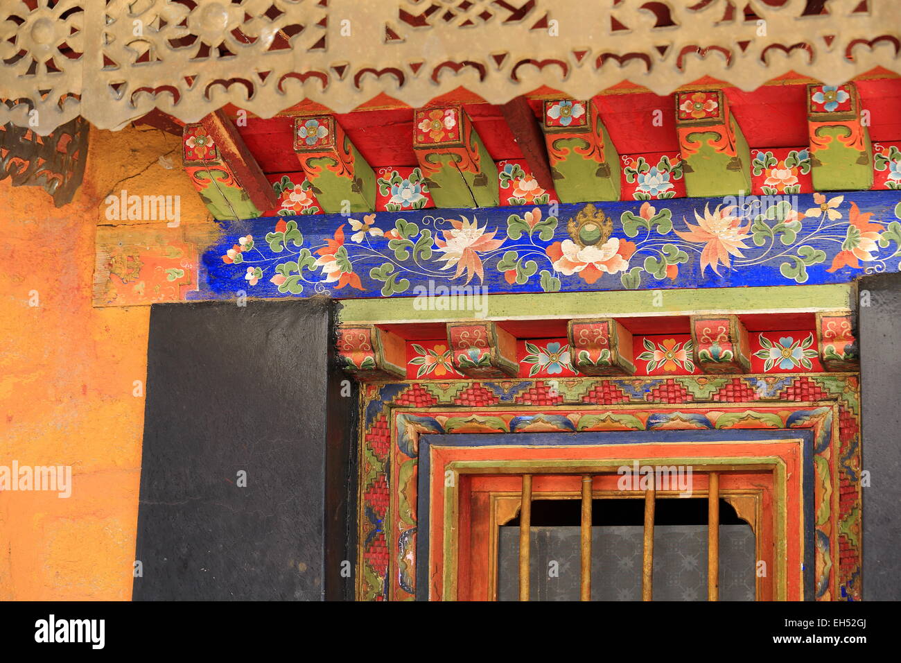 Manycolored sous encadrement de porte en bois peint toit coloriste eaves. Gelugpa-Yellow Drepung-Rice Heap monastère de Hat l'ordre. Le Tibet. Banque D'Images