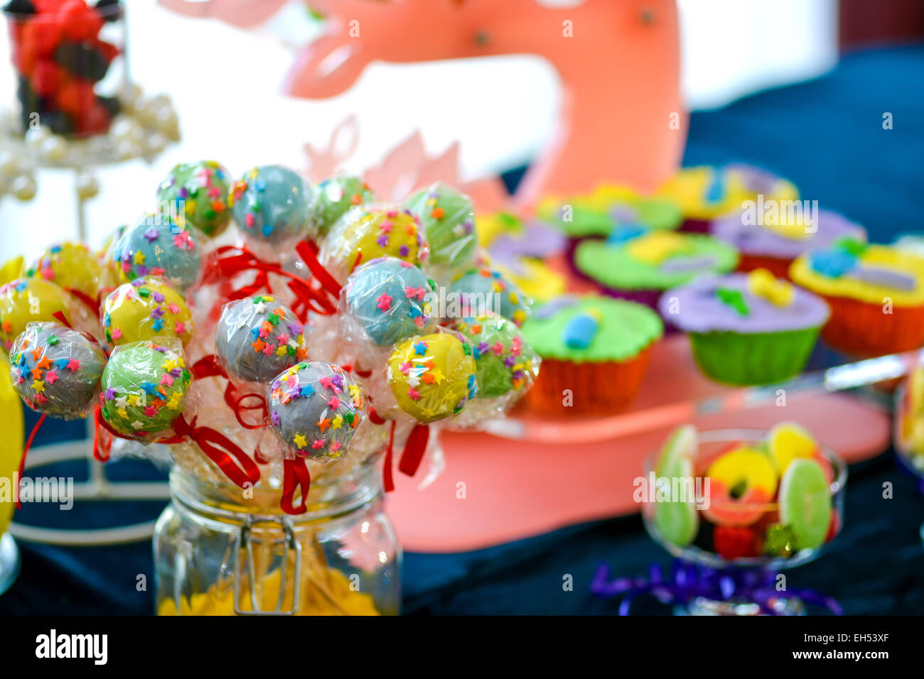 Sucettes colorés placés dans un bocal en verre sur une table pleine de bonbons Banque D'Images