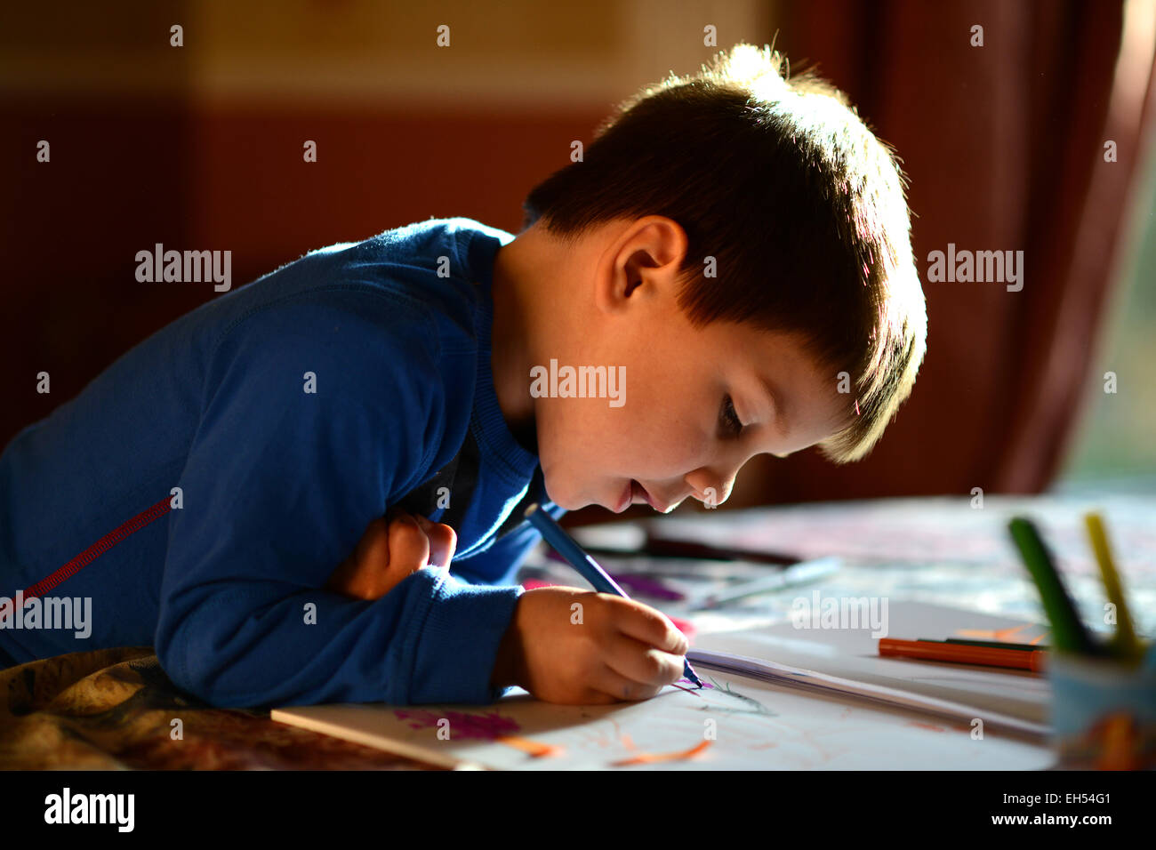 Jeune garçon enfant enfants dessin peinture écrit concentrant uk Banque D'Images
