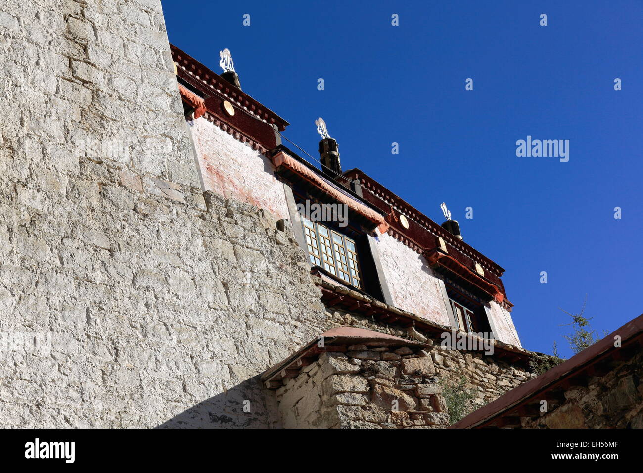 Des murs en pierre et des bâtiments blanchis à la chaux avec dhvaja-victoire bannières sur le toit de l'Drepung-Rice Heap monast. Gelugpa-ord-Tibet Banque D'Images