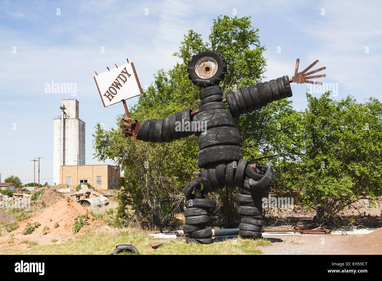 Sculpture d'un homme fait à partir d'auto, camion et les pneus du tracteur à Roosevelt, New York tenant une Howdy signe. Banque D'Images