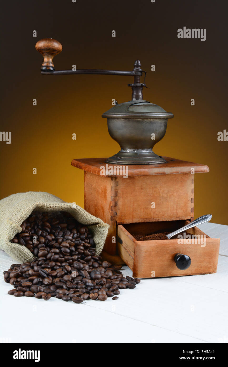 Grain de café la vie encore avec un broyeur et haricots renversé sur une table en bois rustique. Format horizontal avec de la lumière aux teintes chaleureuses Banque D'Images