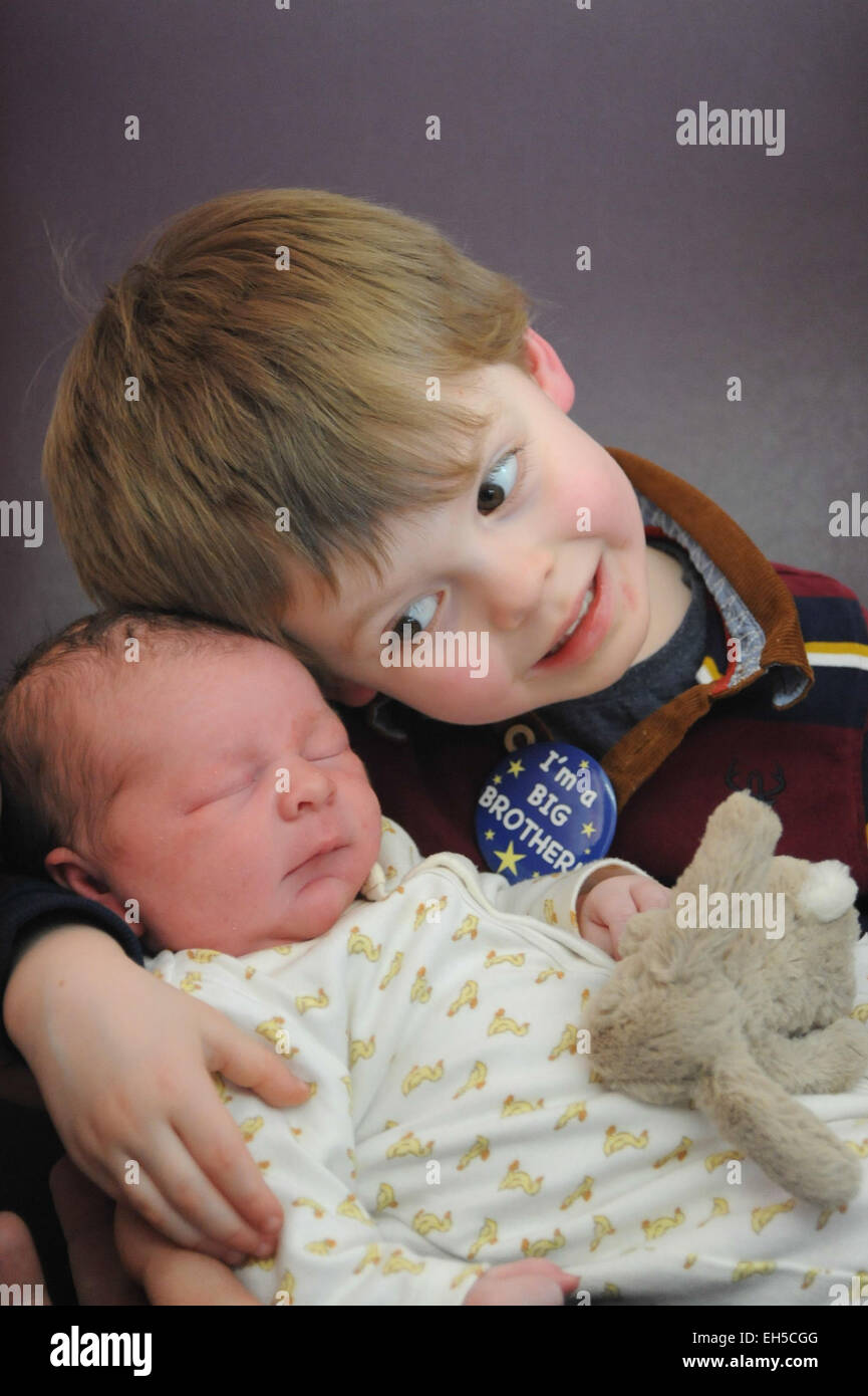 Un grand frère répond à son petit bébé nouveau-né frère pour la première fois à l'hôpital Banque D'Images