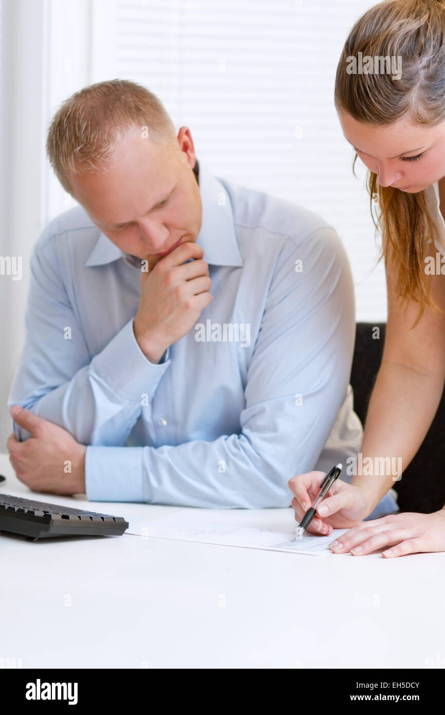 Une femme et un homme d'affaires et planification de discuter. Pointage et regardant un diagramme imprimé sur une table Banque D'Images