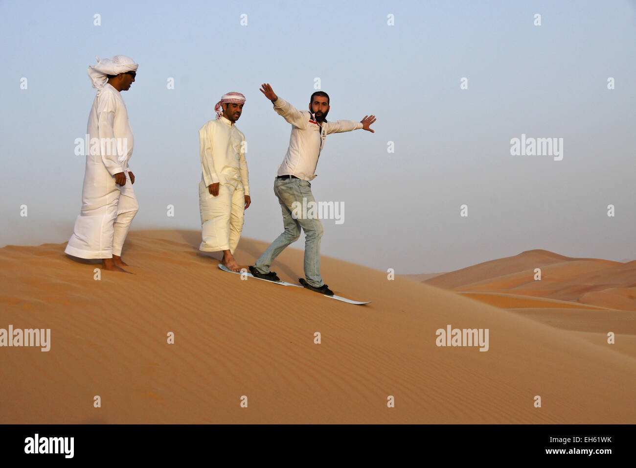 Les hommes arabes 'snowboarding' dans les dunes de Liwa, Abu Dhabi, UAE Banque D'Images