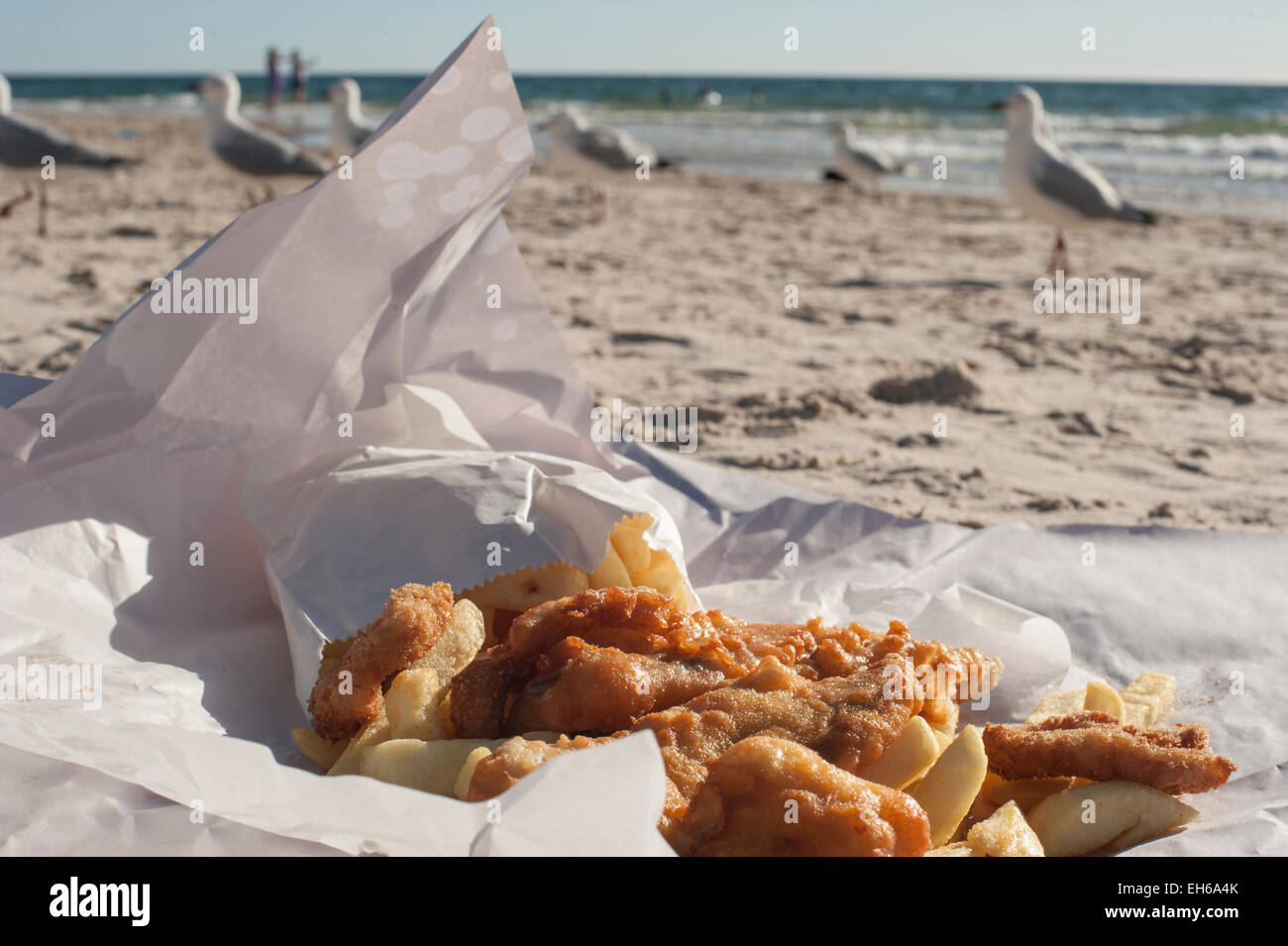 Fish and Chips sur la plage à Adelaide, Australie du Sud, avec les mouettes et l'océan en arrière-plan. Banque D'Images