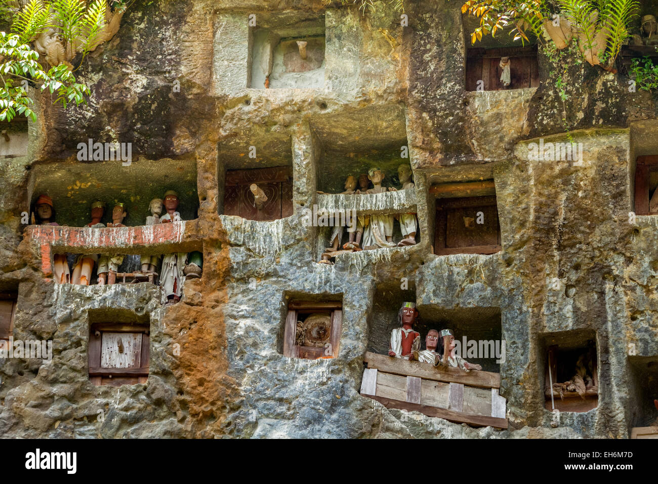 Des ouvertures en pierre et des effigies en bois sur une falaise dans un lieu de sépulture traditionnel à Lemo, au nord de Toraja, au sud de Sulawesi, en Indonésie. Banque D'Images