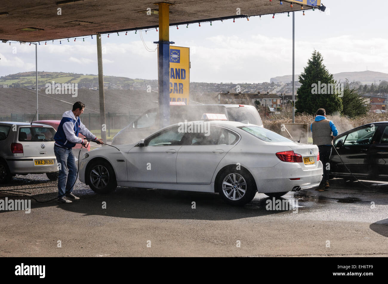 Les hommes se laver les voitures avec les rondelles de puissance à un lavage de voiture 'Euro' Banque D'Images