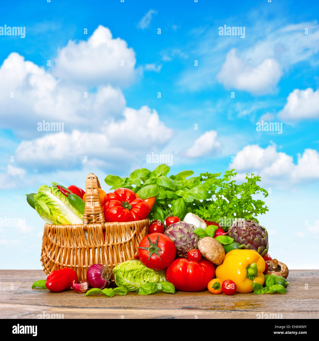 Des légumes frais et des herbes sur fond de bois plus de ciel bleu. Panier avec des ingrédients alimentaires Banque D'Images