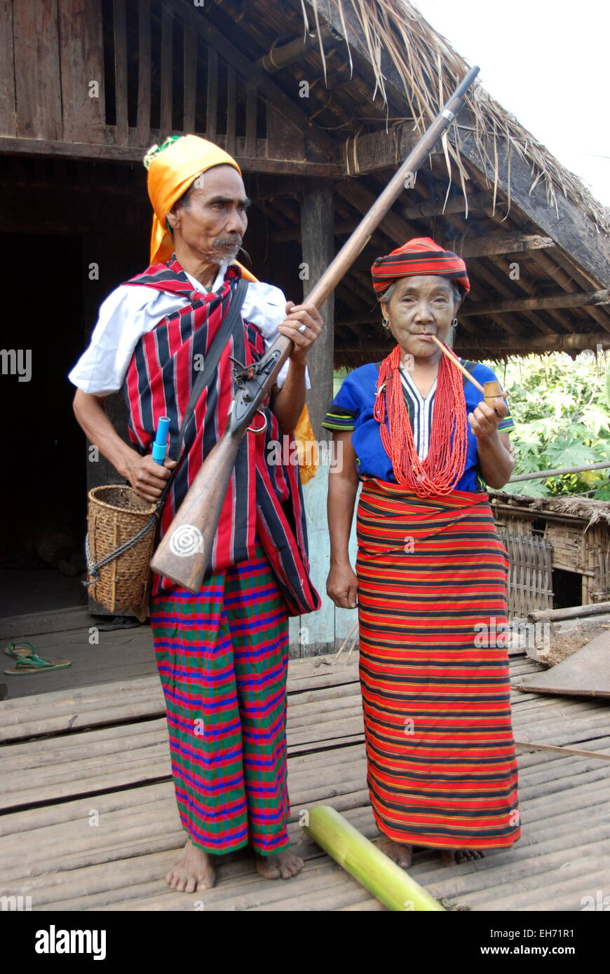 Couple portant des costumes traditionnels tribaux devant leur maison, l'homme avec l'arme à feu, tatoué, dame face Kanpetlet Village Chin Banque D'Images