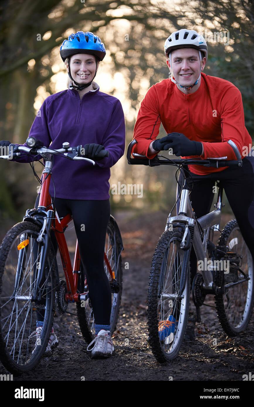 Couple Riding Mountain Bikes à travers des bois Banque D'Images