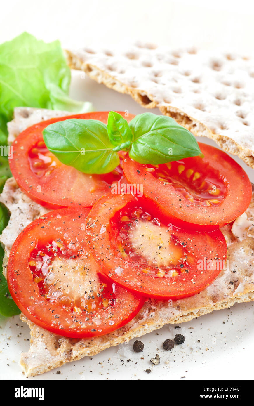 Pain croustillant avec les tranches de tomate. Épicé avec du sel de mer et poivre noir. Banque D'Images