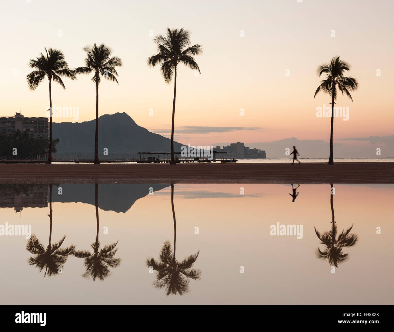 La plage de Waikiki, Oahu, Hawaii - Walker sur la plage au lever du soleil avec Diamond Head derrière Banque D'Images