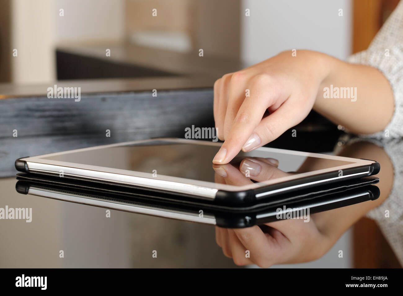 La femme en appuyant sur un écran tactile tablette sur une table à la maison Banque D'Images