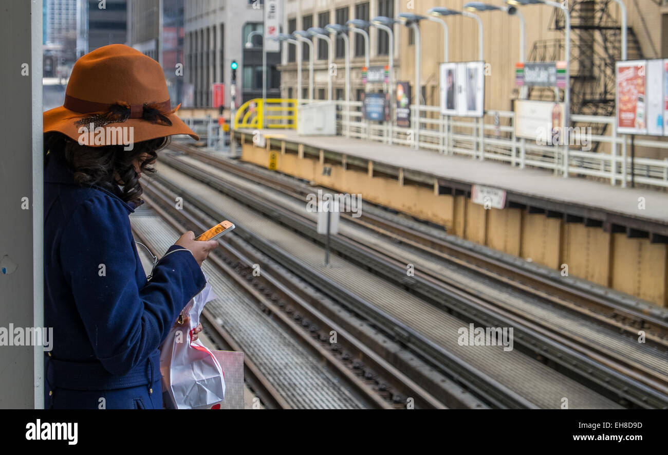 Une fille textes lors d'une Chicago 'L' stop Banque D'Images
