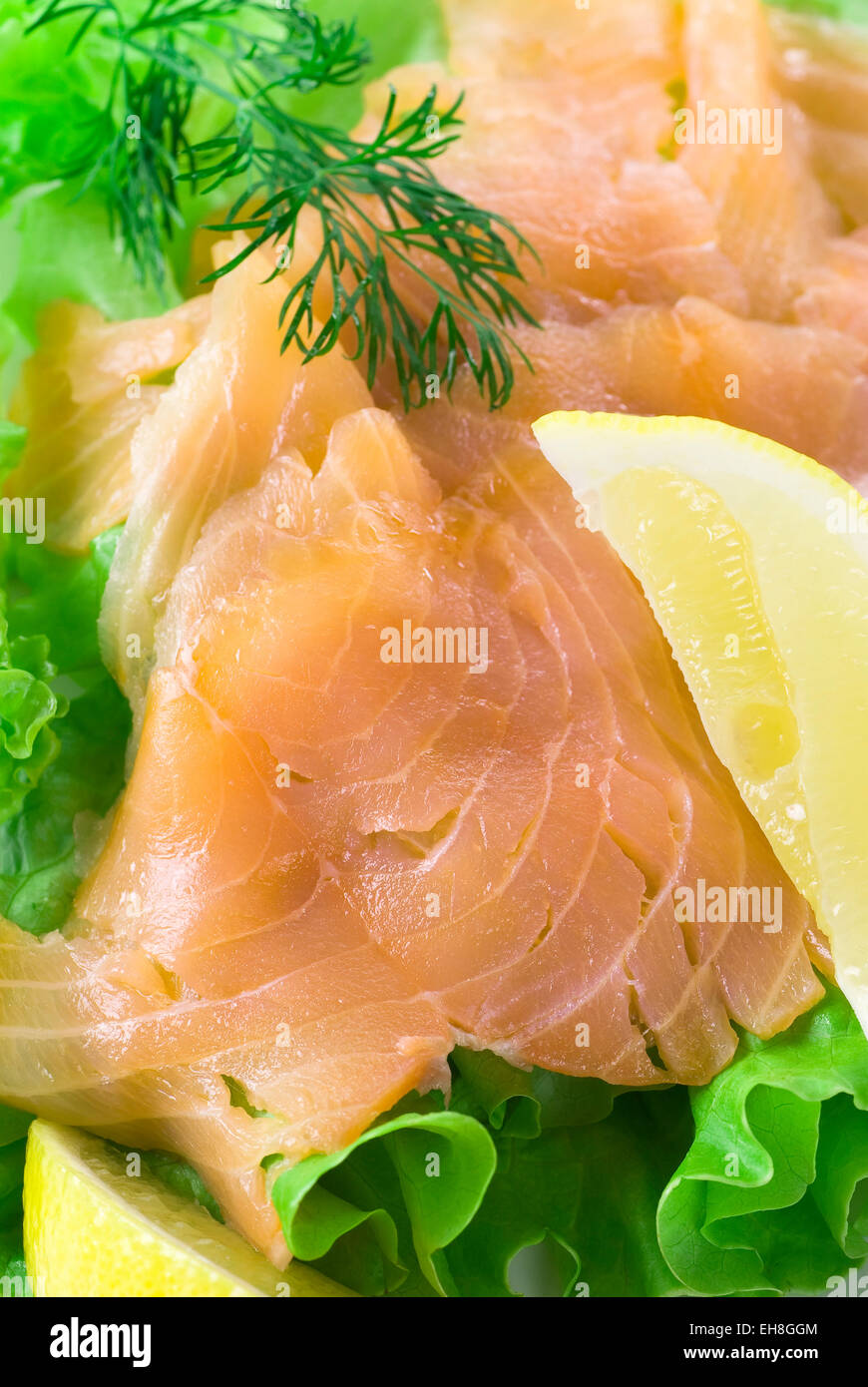 Tranches de saumon fumé sur salade verte. Servi avec du citron et l'aneth. Banque D'Images