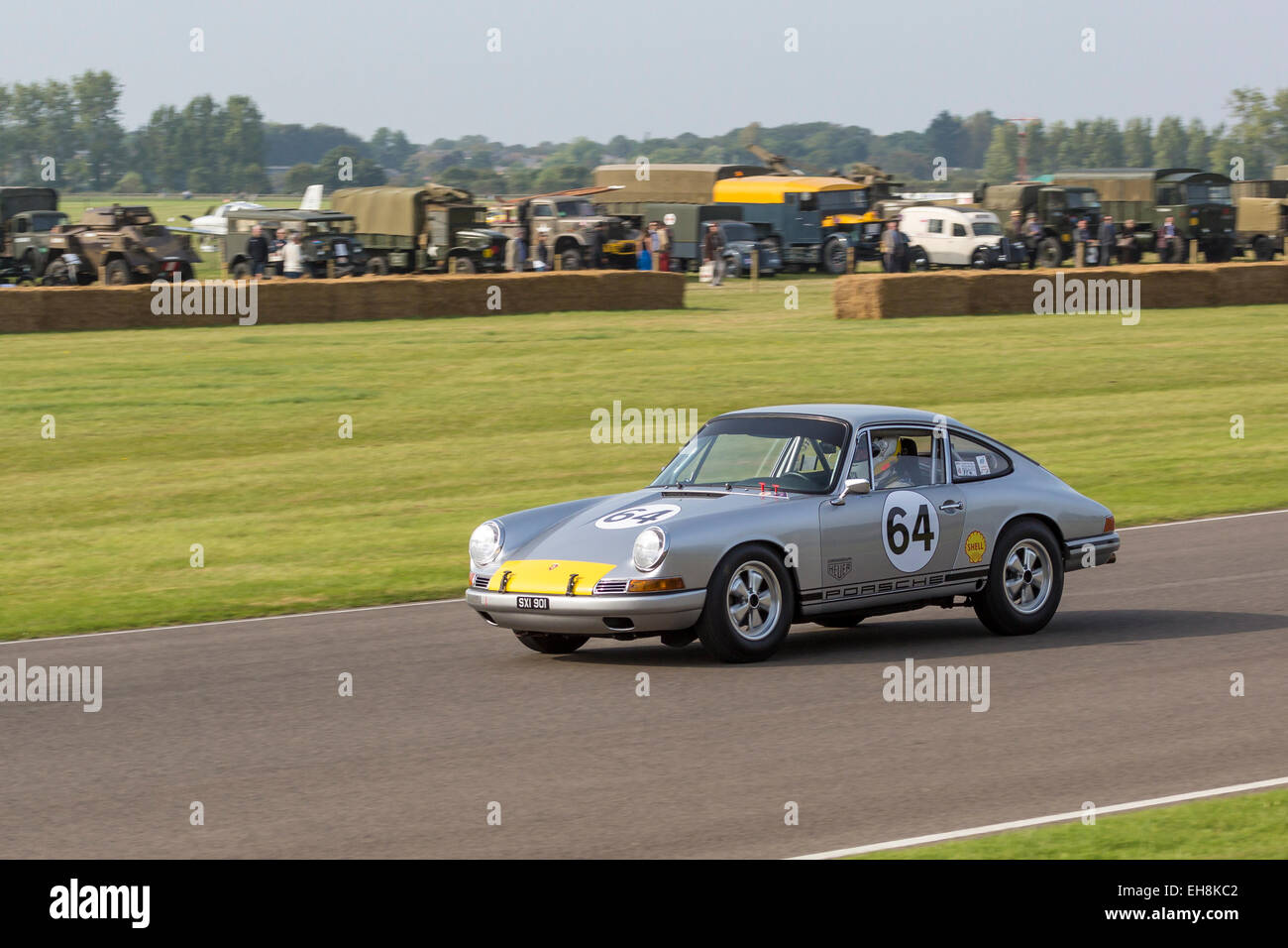 1964 Porsche 901 avec chauffeur Andrew Smith, Fordwater Trophy Race, 2014 Goodwood Revival, Sussex, UK. Véhicule militaire afficher en arrière-plan. Banque D'Images