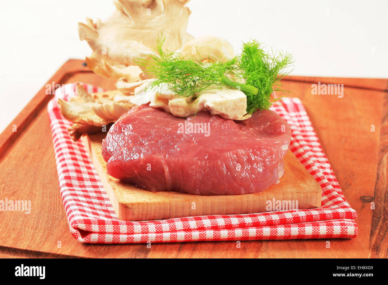 La viande rouge et des pleurotes sur une planche à découper Banque D'Images