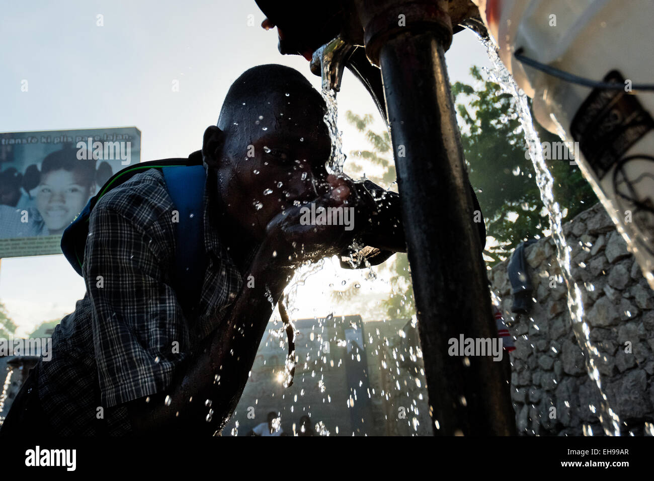 Un homme boit de l'eau potable à partir d'une pompe à eau publique à Port-au-Prince, Haïti. Banque D'Images