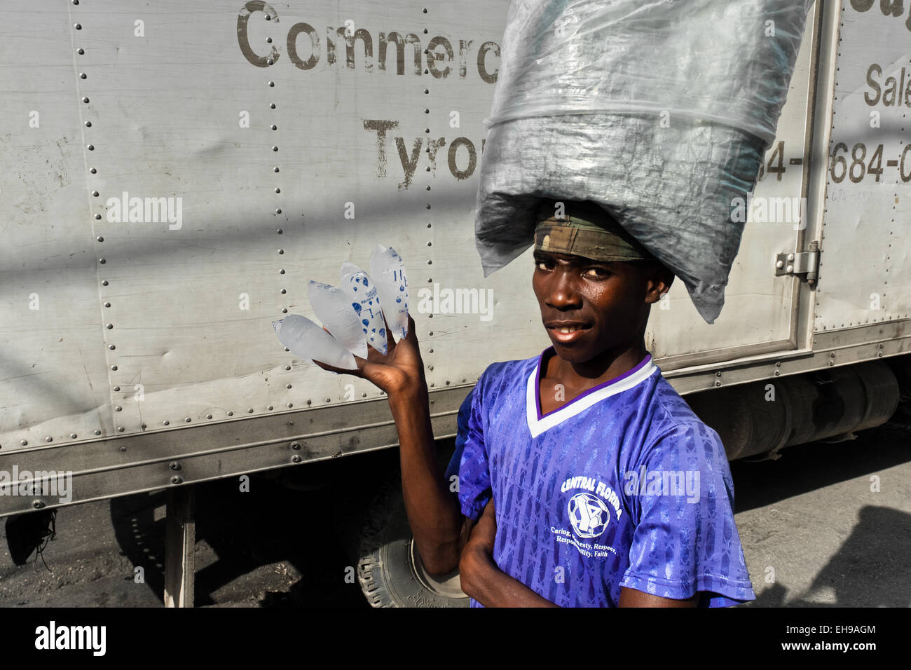 Un garçon haïtien vend de l'eau potable dans des sacs en plastique dans les rues de Port-au-Prince, Haïti. Banque D'Images