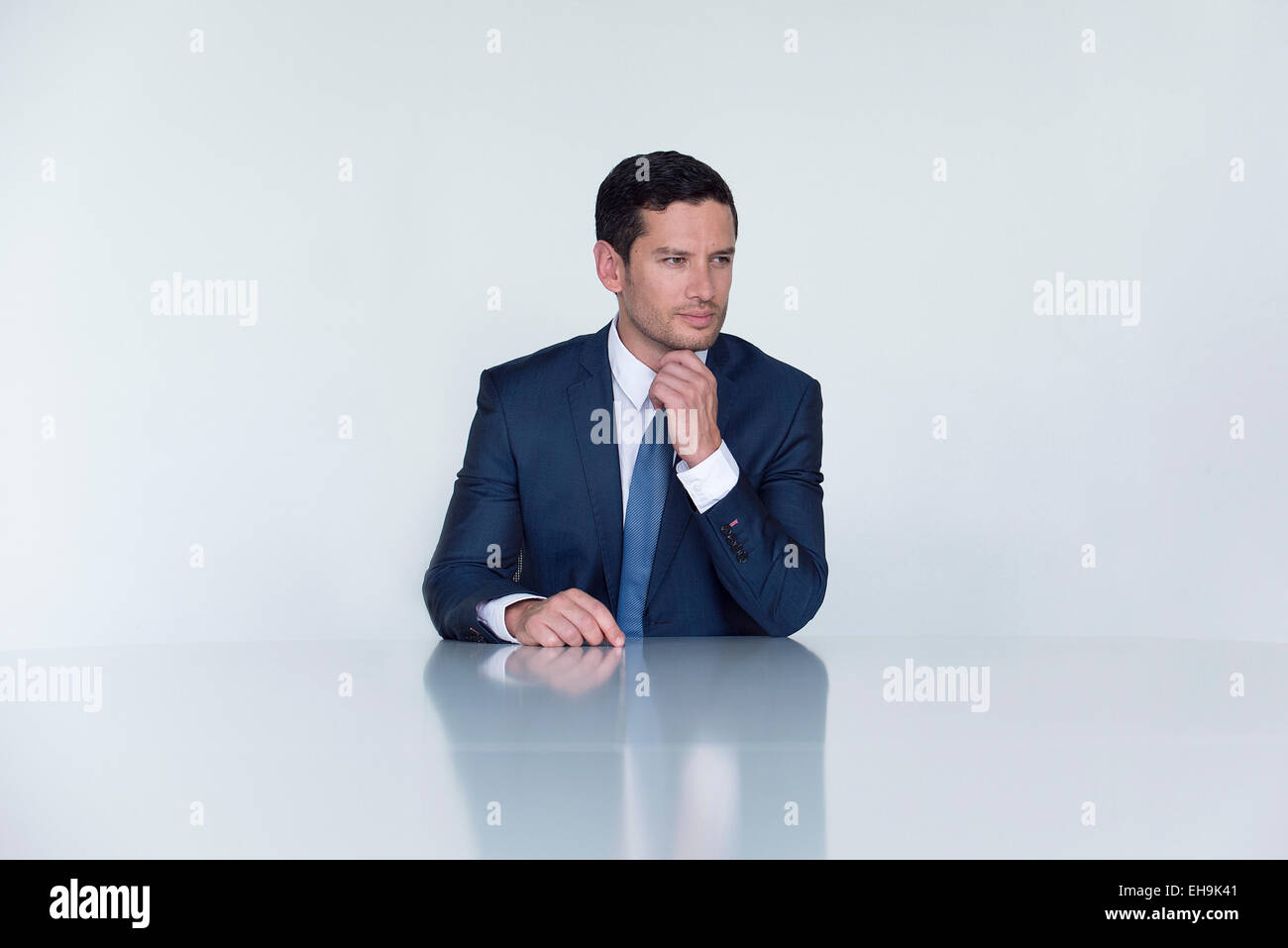 Businessman assis à table, à l'écart dans la pensée Banque D'Images