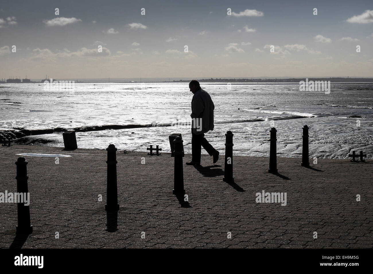 La silhouette d'un homme marchant à Bell quai à marée basse à Leigh on Sea dans l'Essex. Banque D'Images