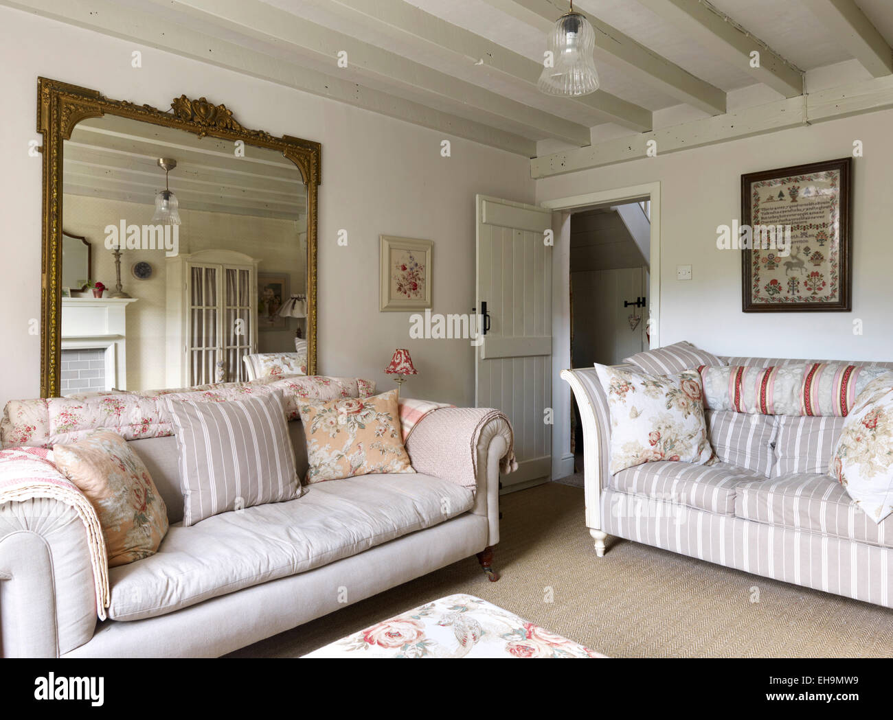 White salon avec poutres au plafond, deux canapés et un grand miroir, maison d'habitation, Belper, Derbyshire Lane, England, UK Banque D'Images