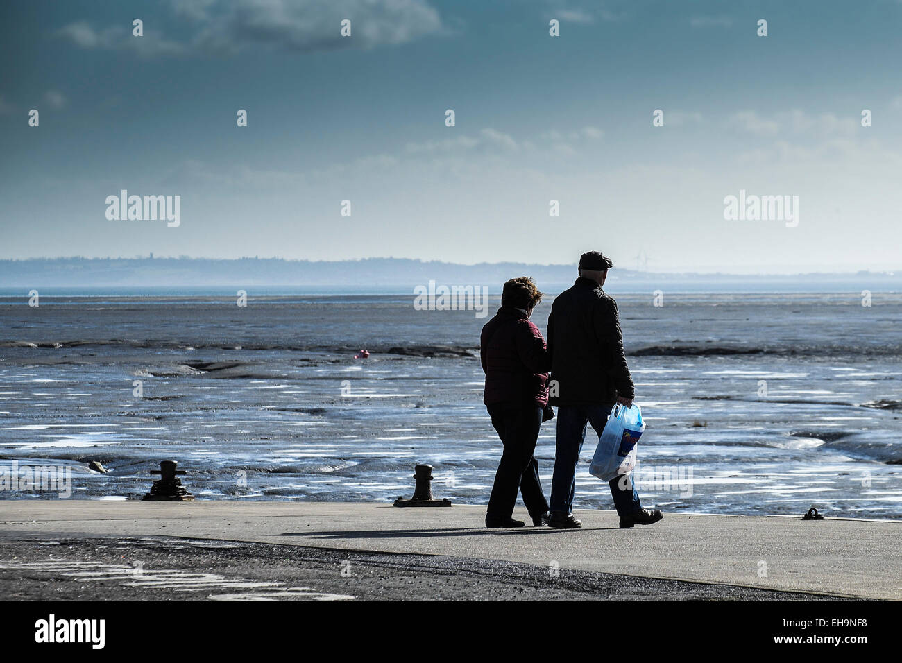 Un couple en train de marcher sur le quai à Bell Leigh on Sea dans l'Essex. Banque D'Images