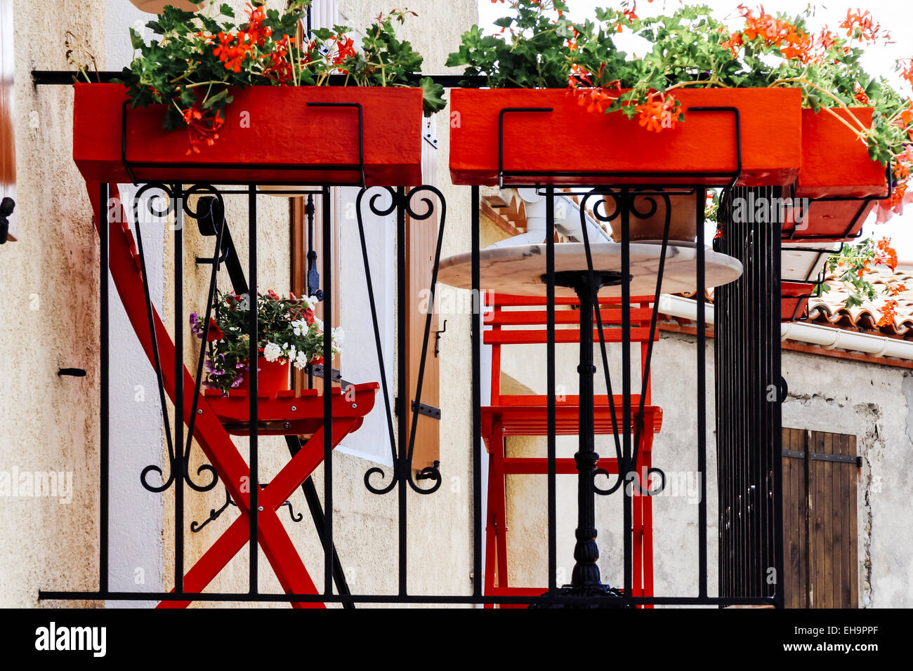 Chaises rouge vif et jardinières sur le balcon de maison du village de Alaigne, Aude, Languedoc-Roussillon, France Banque D'Images