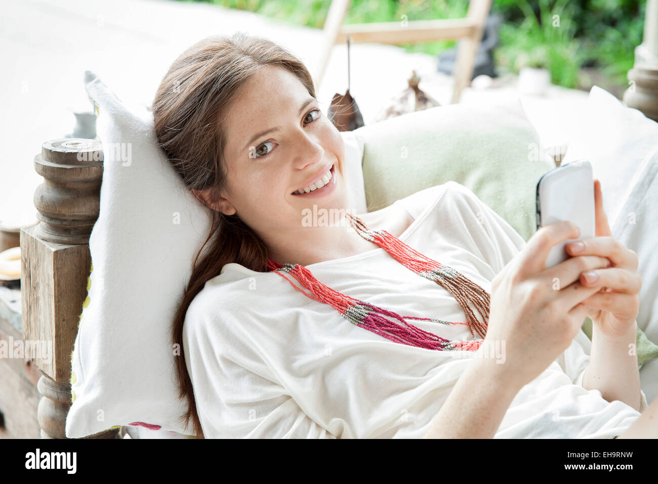 Jeune femme couchée sur le dos avec le smartphone en mains, portrait Banque D'Images