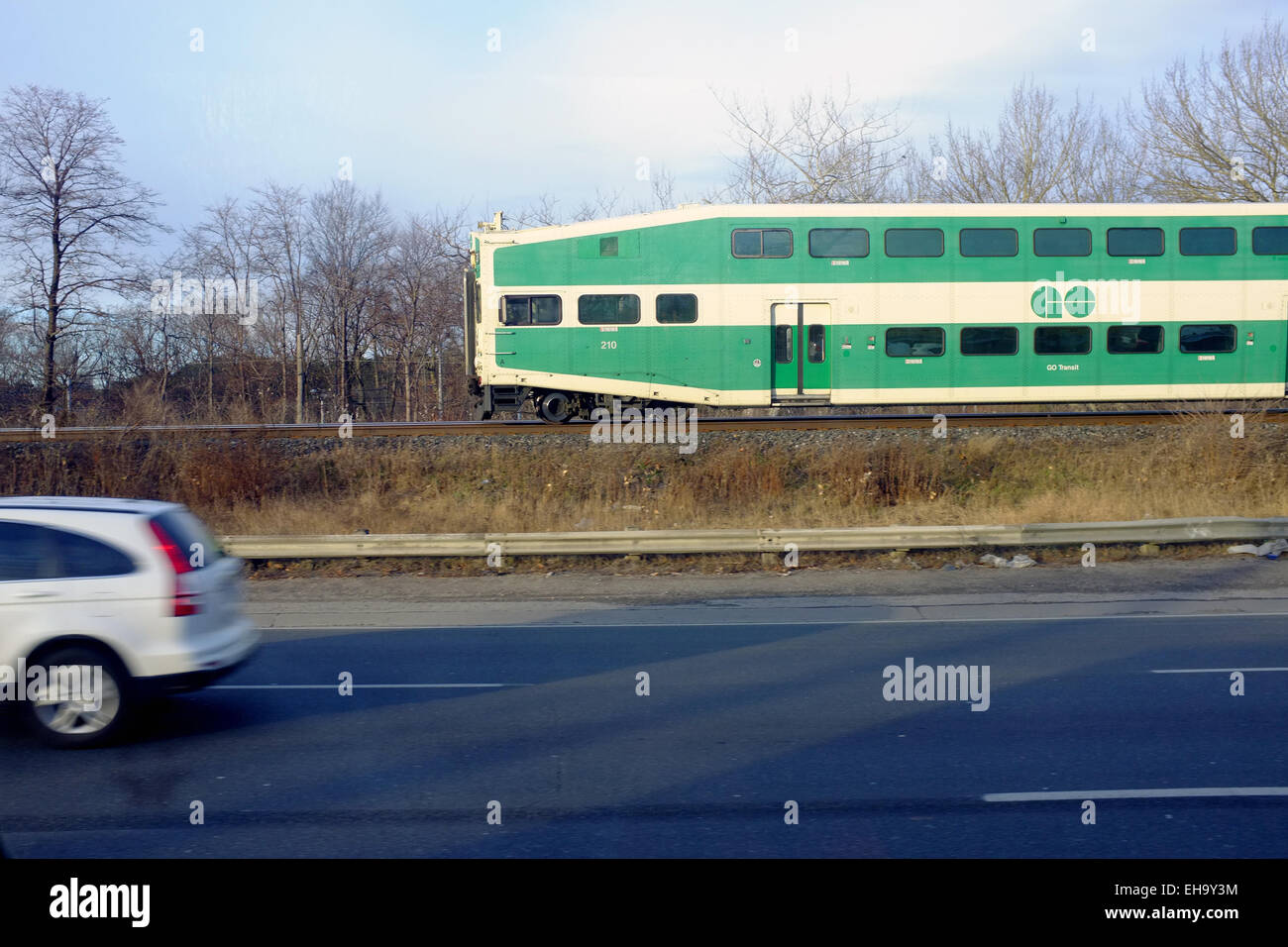 Un double-decker train passe les voitures sur une route au Canada. Banque D'Images