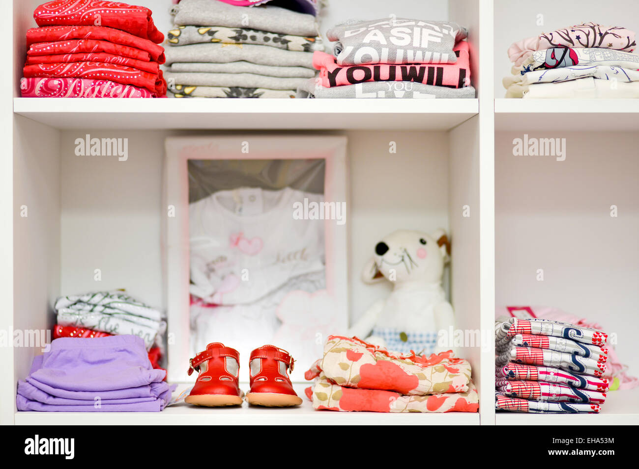 Vêtements de bébé et des chaussures placées sur des étagères en bois blanc Banque D'Images