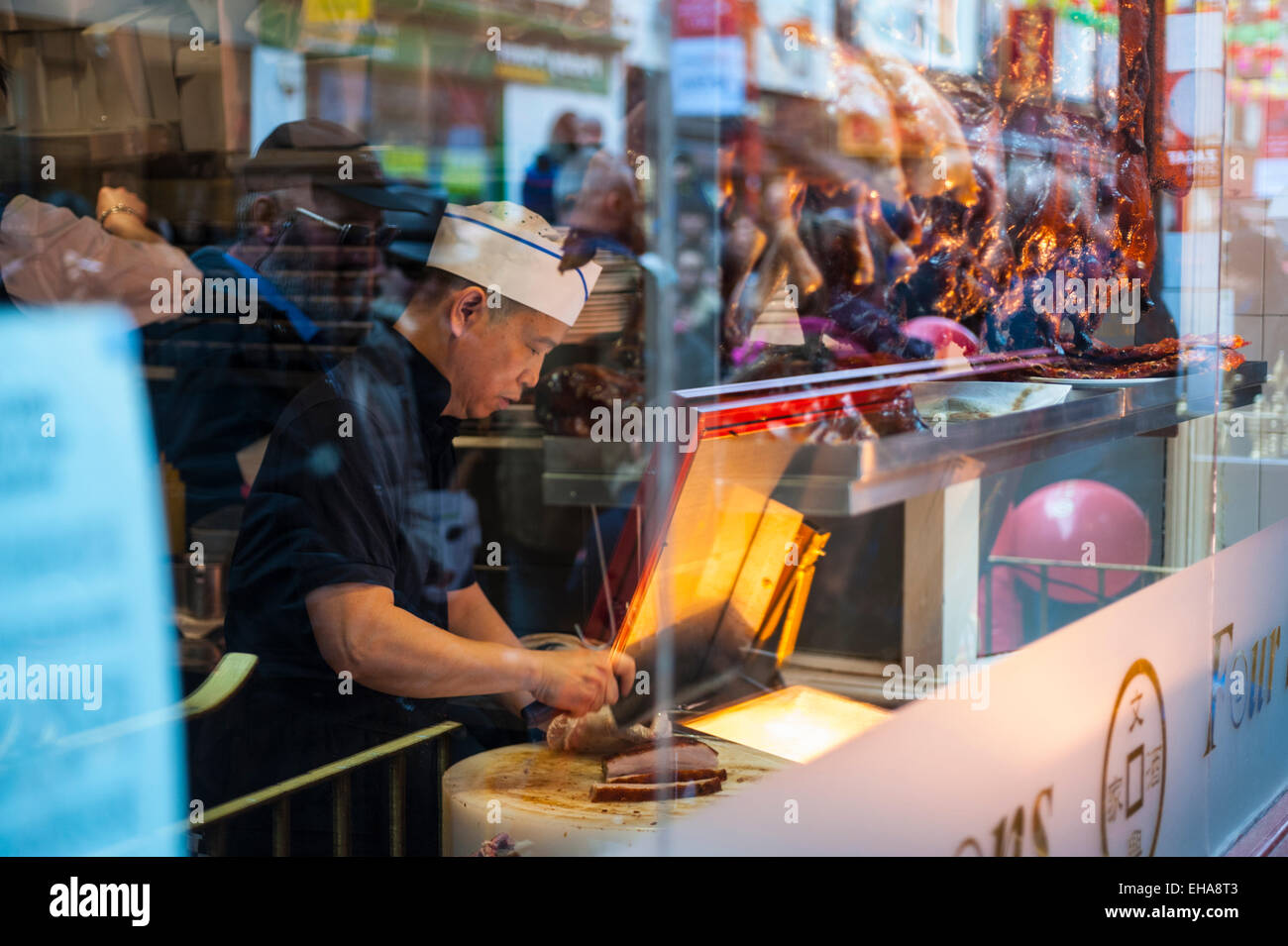 Cuisinier chinois travaillant dans la fenêtre d'un restaurant à Soho Londres Banque D'Images