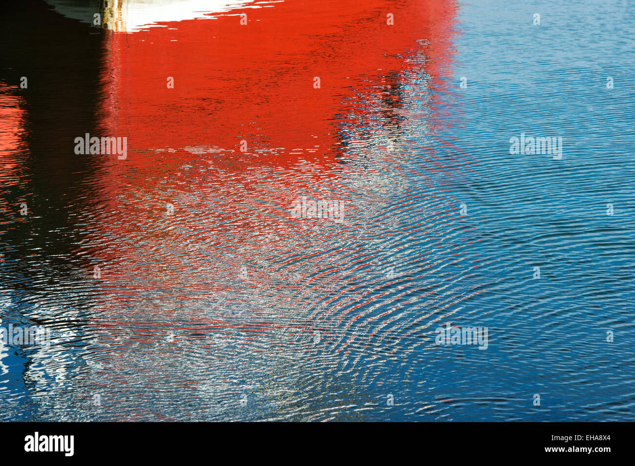 Coque de bateau de pêche rouge et de l'eau reflet à Eyemouth, Berwickshire, Scottish Borders, Scotland Banque D'Images